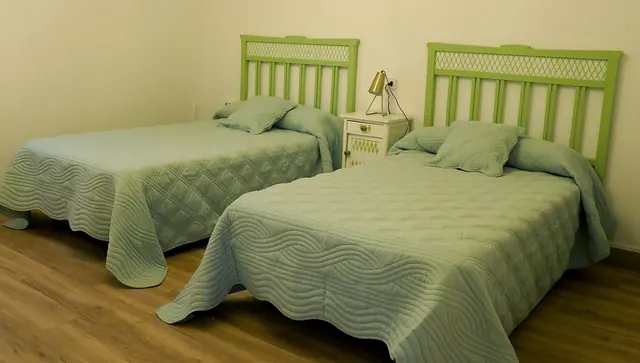 Dormitorio con dos camas y cabeceros verdes