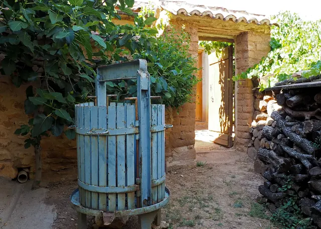 Antigua prensa de uva junto a la leñera del patio